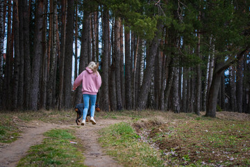 Obraz premium A girl in jeans runs with a Doberman in a pine forest.