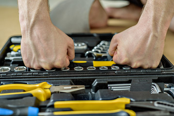 determined man chooses tool from a case for work. Close up