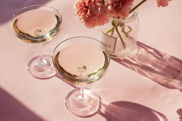 Two glasses of sparkling wine on a pink table