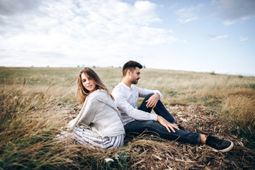 Naklejka na ściany i meble Beautiful loving couple sitting on grass. The guy and the girl hipster travel