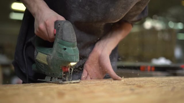  Worker saws a wooden part with an electric jigsaw