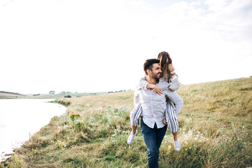 Beautiful loving couple having fun, cuddling, smiling on sky background in field. The guy and the girl hipster travel