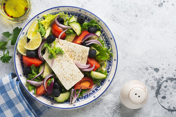 Greek salad in ceramic plate on a white background. Traditional Greek dish. Selective focus. Top view.