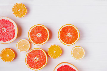 Halves of fresh orange and grapefruit citrus fruits on white wooden background