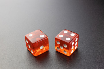 Two red glass dice on a black matte background with side lighting. Two and four with copy space.