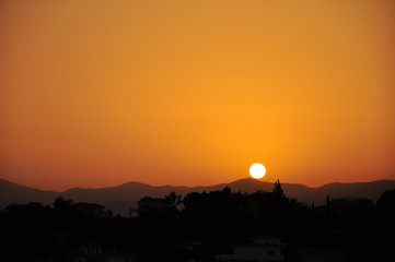 Sunset on a clear sky in orange tones over a mountain range