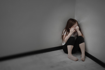 Unhappy Child Sitting In Corner Of Room