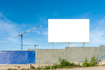 Blank billboard for advertisement on the construction site with cranes on a sunny day © diesirae