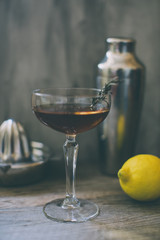 alcohol whiskey cocktail in a coupe glass with lemon and shaker