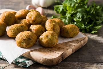 Traditional cod fritters decorated with garlic and parsley on wooden table	