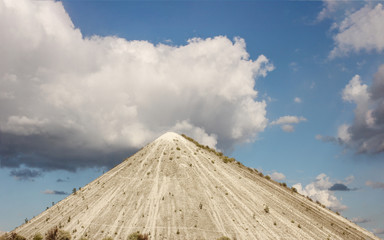 Chalk mountains against a cloudy blue sky in a green field in Ukraine.