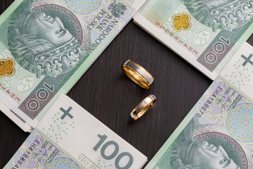 Gold wedding rings surrounded by a stack of Polish banknotes.