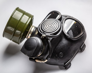 A close up of black commander gas mask with a filter lies on a white background. Horizontal...