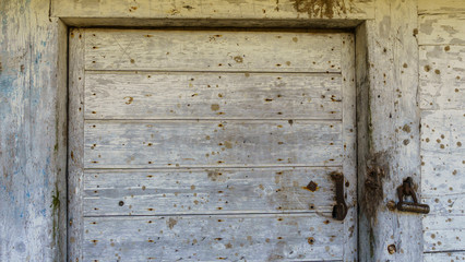 Rustic barn white door. Wooden planks and locks closeup. Peeling paint and weathered. Space for text. Texture and background.