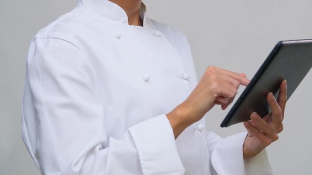 cooking, culinary and people concept - happy smiling female chef in toque with tablet pc computer over grey background