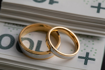 Gold wedding rings surrounded by a stack of Polish banknotes.