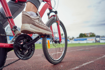 closeup bicycle chain with a pedal and a sneaker on it.