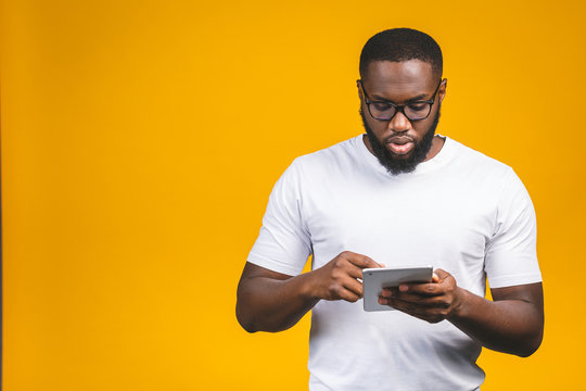 Working On Digital Tablet. Rear View Of Young African American Man Working On Digital Tablet While Standing Isolated On Yellow Background.