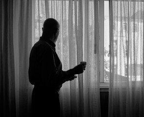 Hombre mira por la ventana de un edificio durante el confinamiento por el coronavirus COVID-19. La prohibición de salir a la calle es el origen de problemas de soledad y depresión en muchas personas.