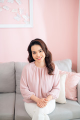 Naklejka premium Attractive young Asian woman sitting on sofa and smiling.