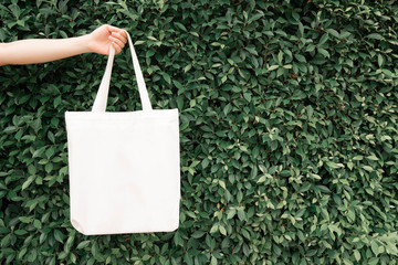 Blank white tote bag canvas fabric with handle mock up design. Close up of woman hand holding eco...