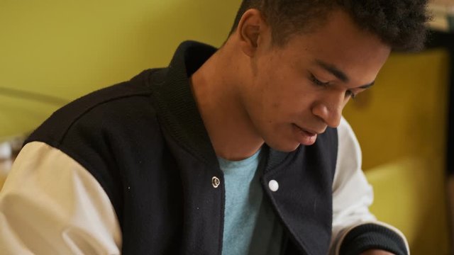 Handsome concentrated young african guy student studying doing homework.