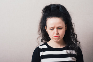 Woman sad, offended. Gray background