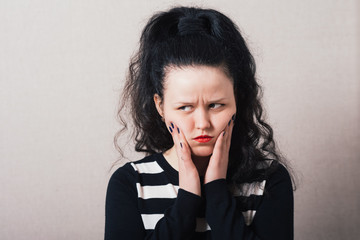 Woman sad, offended. Gray background