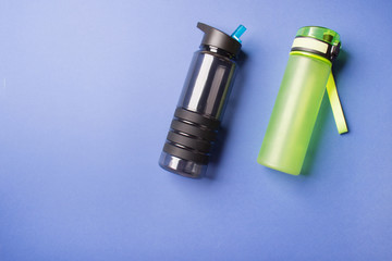 black and green sport plastic bottles lying on blue colored paper background with copy space