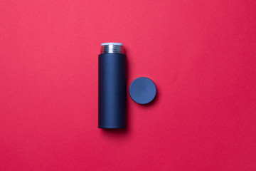 black thermos cup with open cover on red background