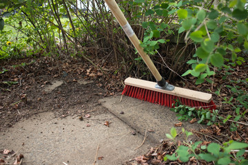 Garden broom brush with a pile of leaves in a garden yard.