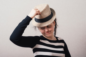 Woman takes off his hat and clothes. Gray background.