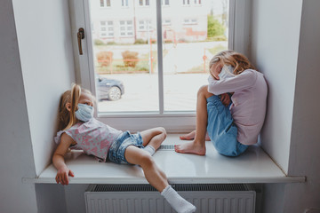 UPSET white girls are sad in quarantine wearing masks against coronavirus. the children stayed at...