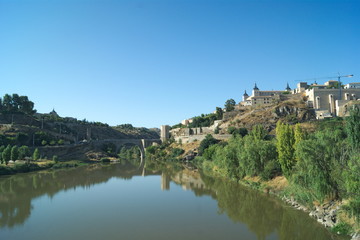 Fototapeta na wymiar Spain, Toledo, the beautiful, historic Alcantara bridge. The monument is reflected in the still waters of the river Tagus.