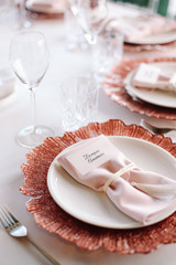 Wedding. Banquet. Glass table with pink and white flowers and red and white plates on it, served with cutlery, flowers and crockery.