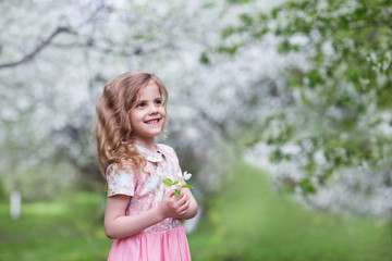 Fototapeta premium girl in a pink dress smiles in a blooming garden