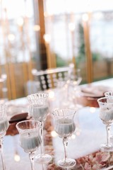 Wedding. Banquet. Glass table with pink and white flowers and red and white plates on it, served with cutlery, flowers and crockery.