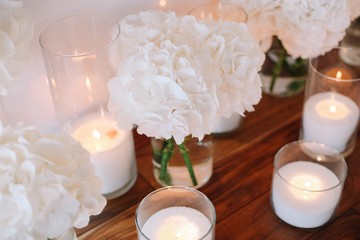 Fototapeta na wymiar Flower arrangement, crystal, glass candles decorate banquet hall. White hydrangea and candles.