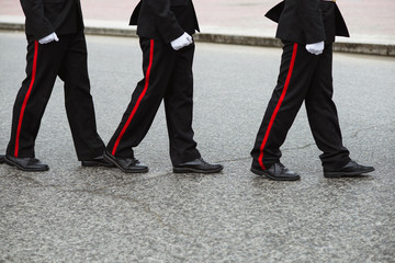 Three Russian cadets in a ceremonial black uniform go one after another. Crop by waist. People in uniform