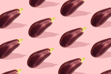 Flat lay colorful pattern with eggplant on pastel pink background. Trendy mockup or wallpaper. Minimal healhty lyfestyle concept with sharp shadows.