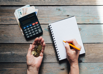Close up of woman's hands writing in spiral notepad on wooden background