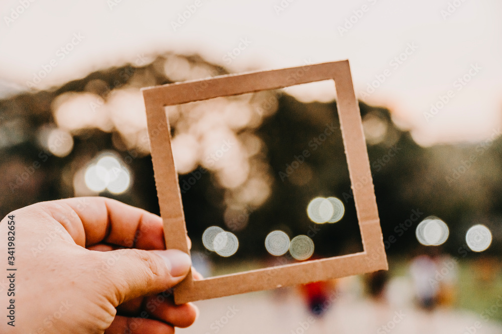 Wall mural hand holding blank paper frame with nature bokeh background