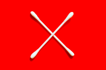Two white cotton buds on a red background forming a cross.
