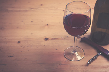 Glass of red wine with a bottle on a wooden background