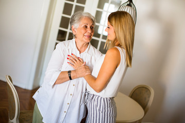 Fototapeta premium Young woman and her grandmother standing in the room