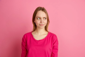 Doubt, uncertainty. Caucasian young woman's portrait isolated on pink studio background, monochrome. Beautiful female model. Concept of human emotions, facial expression, sales, ad, trendy.
