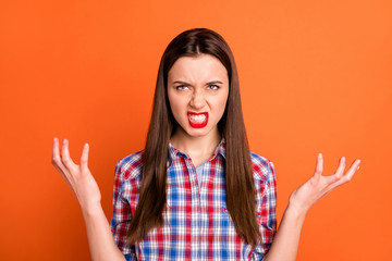 Photo of attractive but evil lady look empty space rage raising arms very angry with irritating situation wear casual checkered shirt isolated bright orange color background