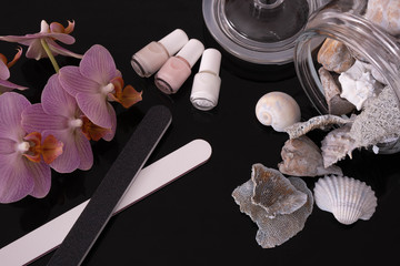Obraz na płótnie Canvas on a glass table lies nail polish, orchid, nail files and shells