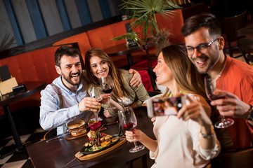 Handsome young friends making selfie and smiling while having a dinner in restaurant