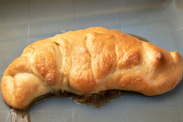 Unsuccessful baking, apple jam leaked from the bun. Close-up.